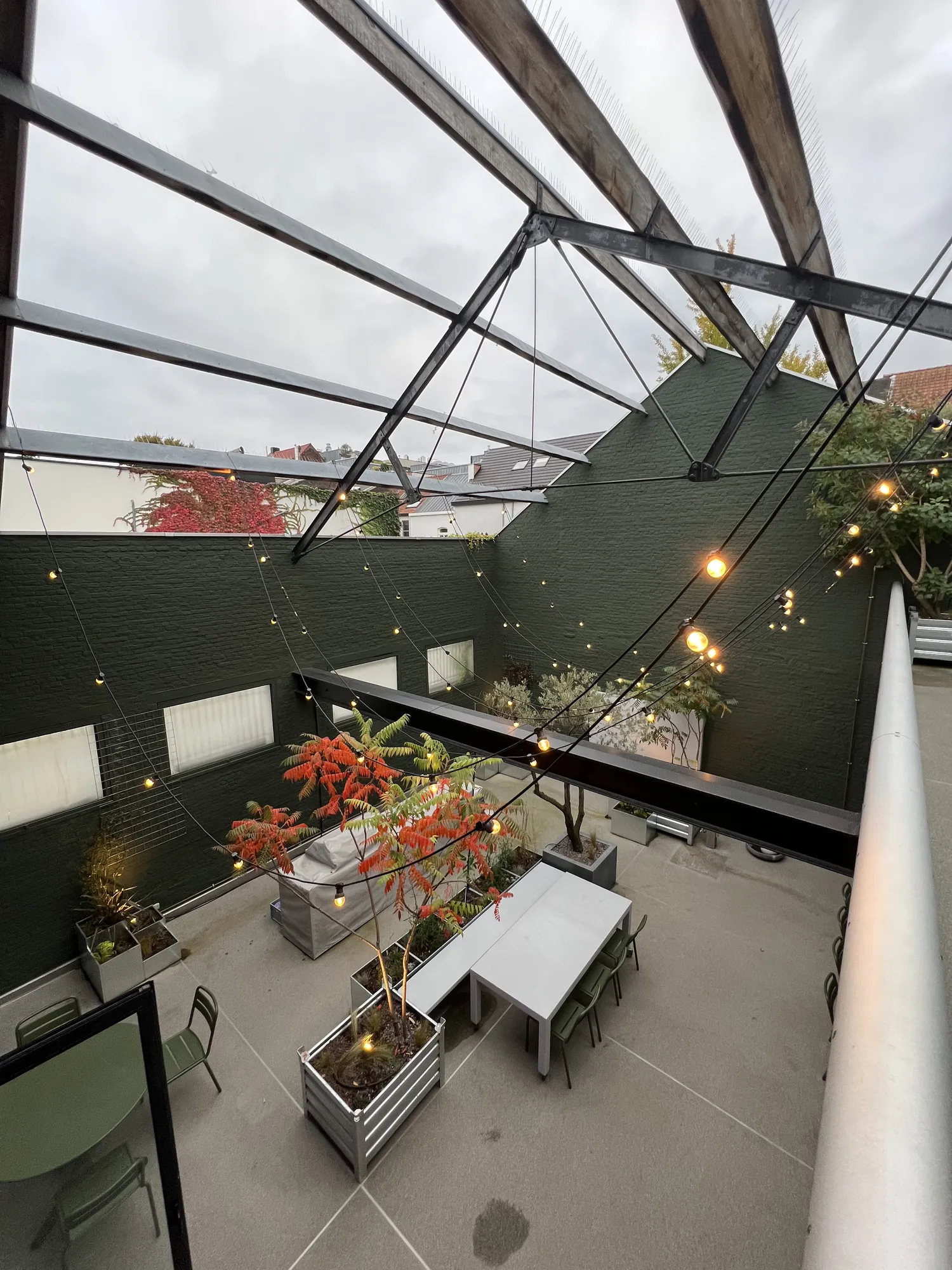 The Terrace bij daglicht, met tafels, planten en open dak